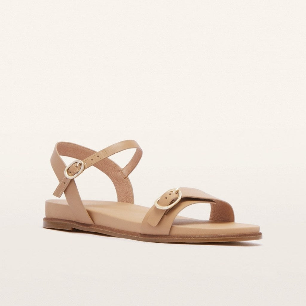 Beige sandal with a gold buckle on a light beige background